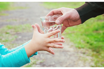 The father gives the child a glass, a Food & Drink Photo by yanadjana