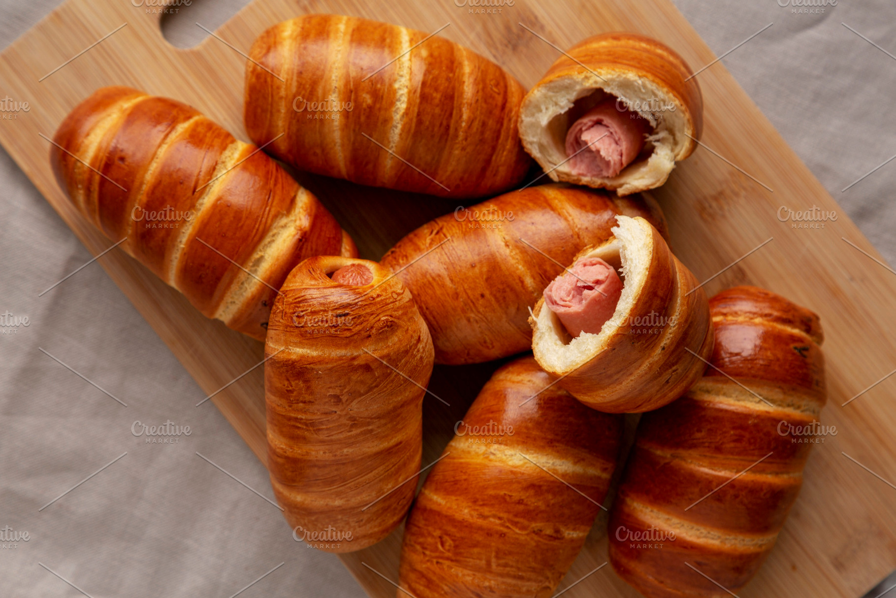 Homemade Sausage Buns on a bamboo board, top view. Flat lay, ove, a Food & Drink Photo by LiudmylaChuhunova