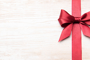 Red festive bow and ribbon on wooden background, a Holiday Photo by Olena Rudo