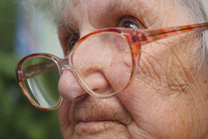 Old woman in glasses looking forward. Granny wearing eyeglasses outside. Portrait of grandmother outdoor. Close up Side view Slow motion