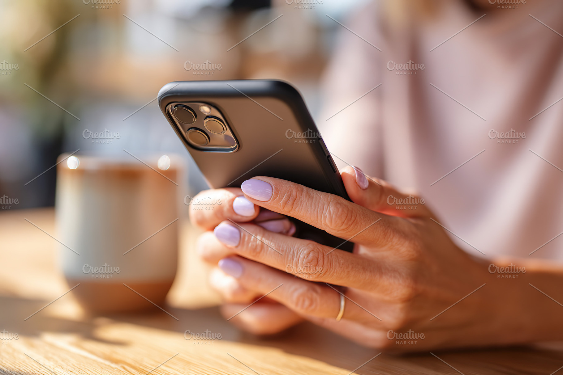 Woman using smartphone while seated at a wooden table in a cozy cafe environmen, a Photo by AlyaAnd