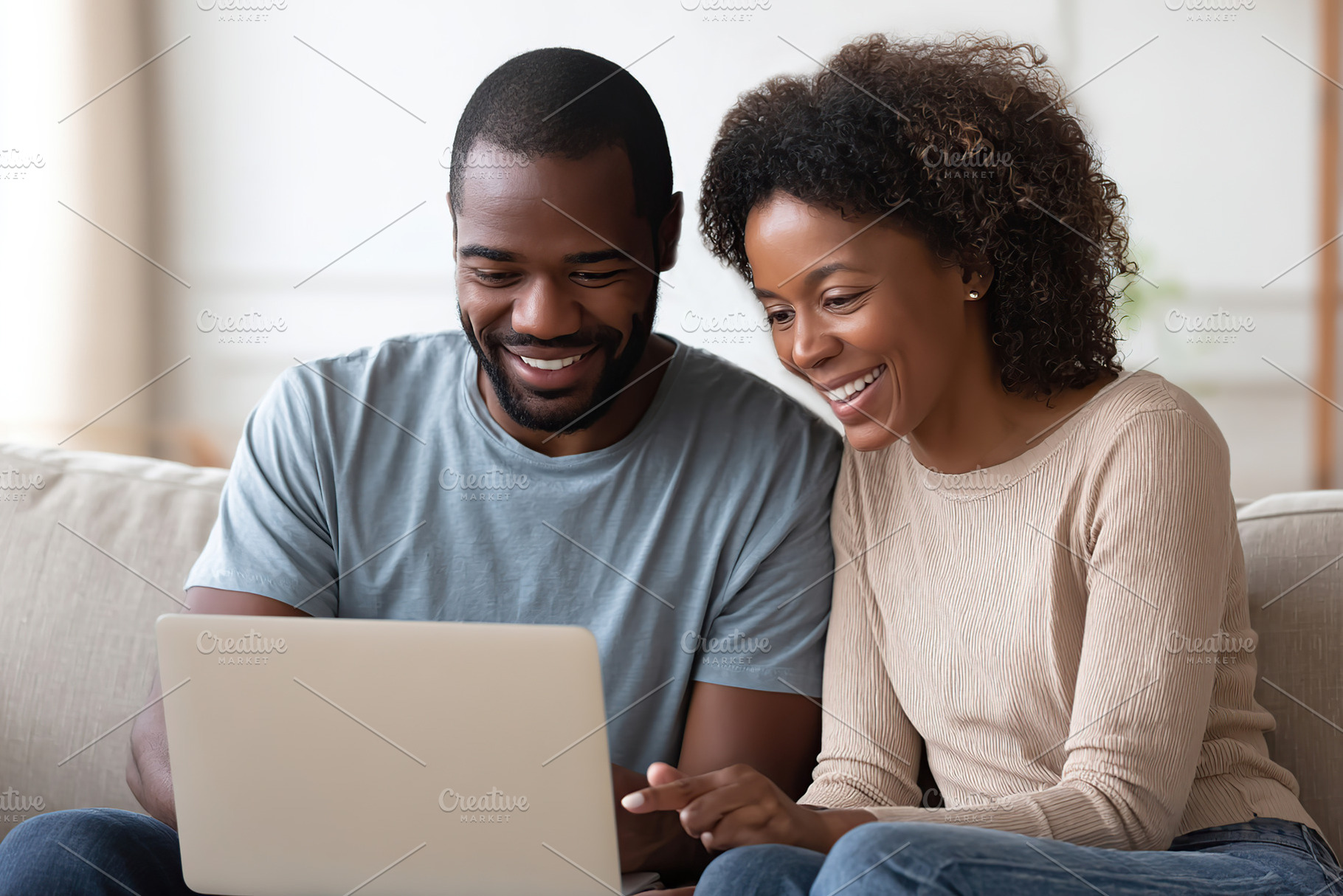 Couple enjoying a joyful moment while using a laptop in a cozy living room, a Photo by AlyaAnd