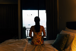 Young woman in a bedroom looking out, a Person Photo by AMMi
