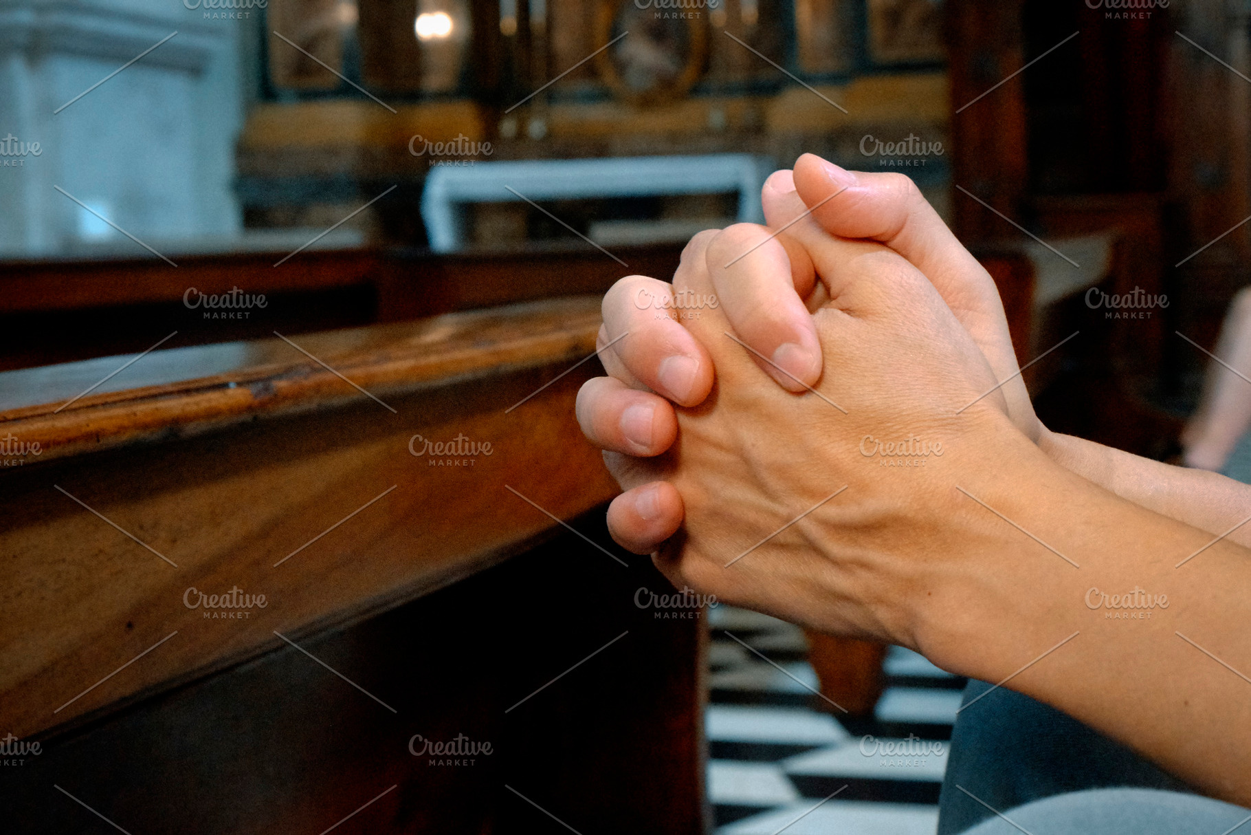 man praying in a church with intertwined hands, a Photo by Nito