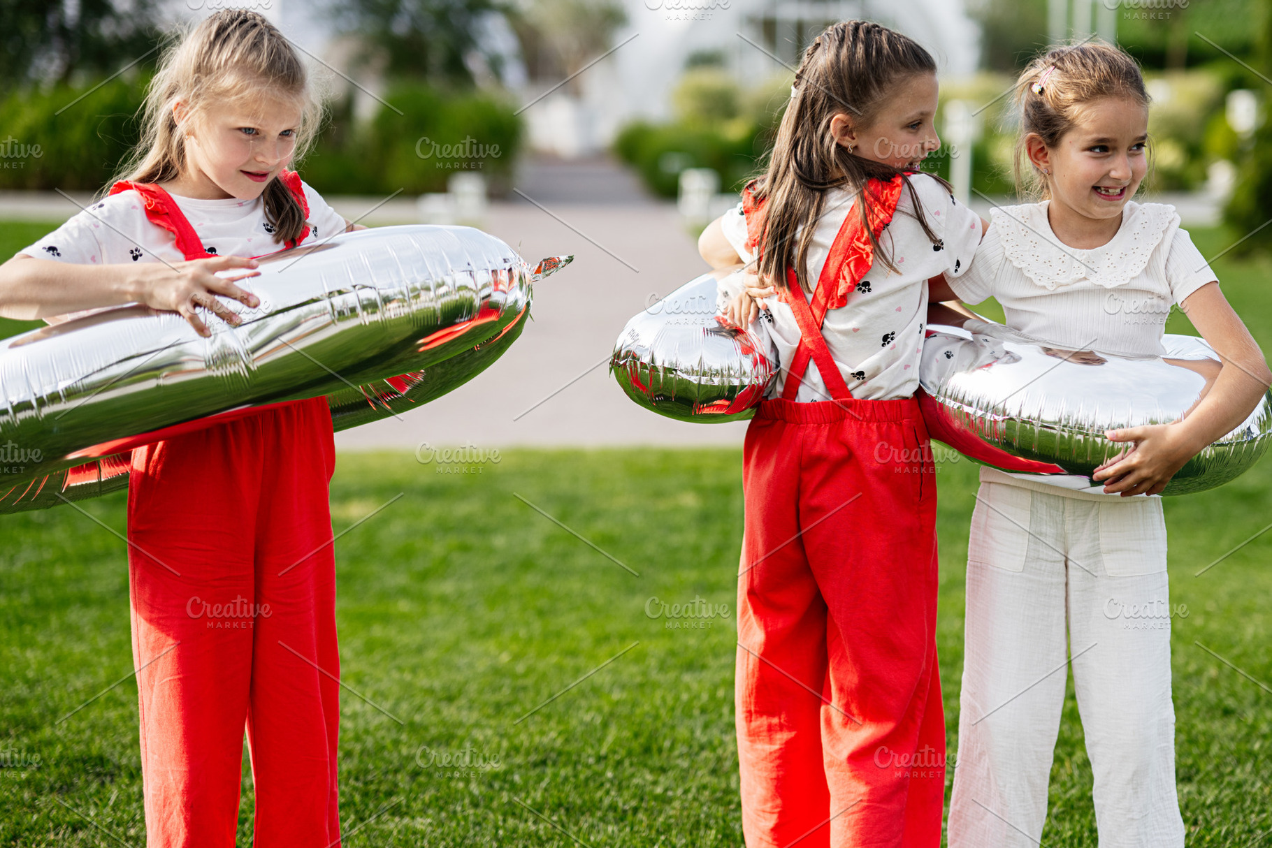 Three children playing with shiny balloons outdoors on a sunny day, a Photo by AS photostudio