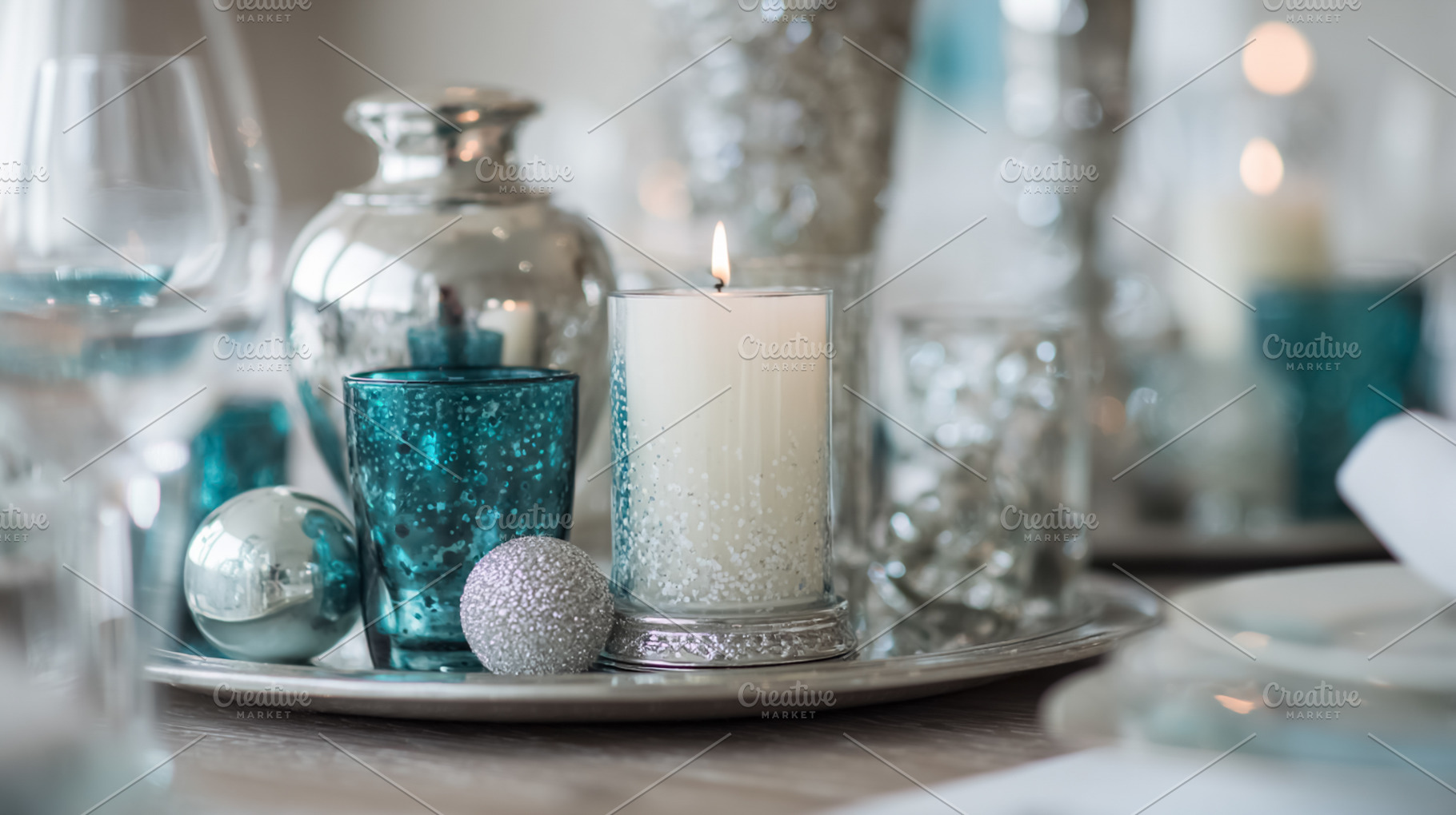 Elegant silver and turquoise table centerpiece with lit candle,, a Photo by Studio ANNA