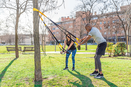 Fitness couple doing arms exercise with trx fitness straps in park, a Sports & Recreation Photo by Iván Moreno STOCK PHOTO