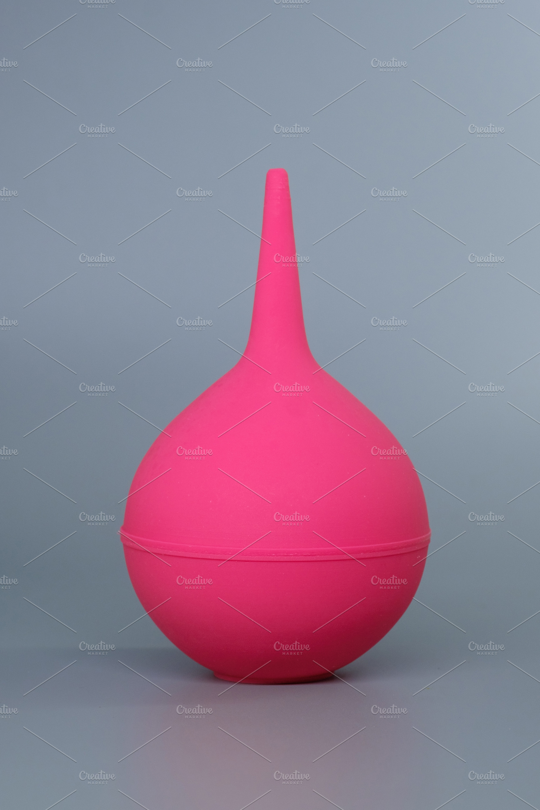Pink rubber medical syringe bulb on a grey background. Disposable rubber enema, a Health & Medical Photo by Rohan Photography