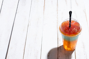 Colorful Frozen Slushie Drink in Plastic Cup on White Wooden Table, a Food & Drink Photo by etorres69