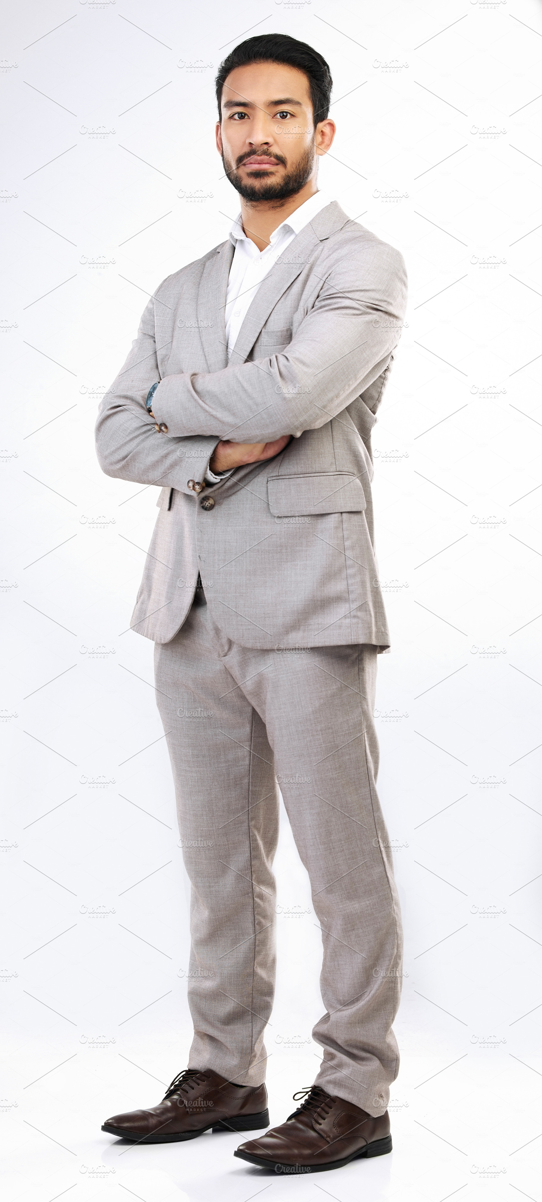Serious, business man and portrait of arms crossed in studio, white background and leadership. Focused male model, entrepreneur and professional corporate worker with pride, power and suit of boss, a Photo by Peopleimages.com