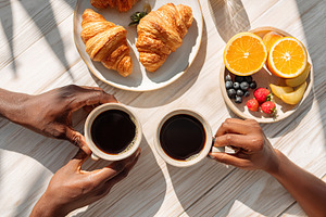 Enjoying coffee and fresh breakfast items with friends in a sunny cafe setting, a Photo by AlyaAnd