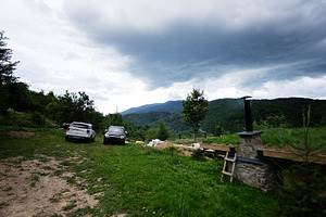 Two parked cars in a lush mountainous countryside under cloudy skies, a Photo by AS photostudio