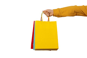 Close-up of a hand holding bright shopping bags on a white backg, a Holiday Photo by Ales Munt