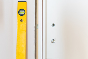 Construction worker using spirit level installing white door in a house, an Architecture Photo by Antonio Gravante Market