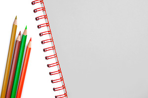 Colorful pencils on white notebook, a School & Education Photo by BOOCYS
