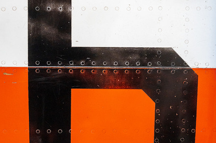 Large black number -6- on an old aircraft fuselage with rivets