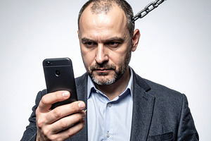 Man chained to smartphone, a Technology Photo by DanFLCreativo