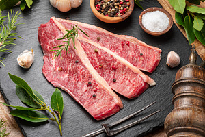 Sliced picanha beef with spices and herbs on a gray stone servin, a Food & Drink Photo by Volff