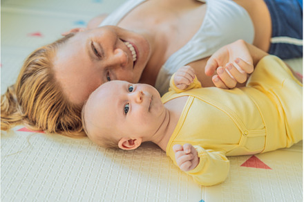 Mother and baby lying on a play mat