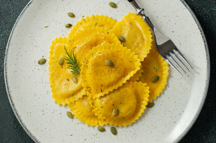 Homemade Pumpkin Ravioli with butter on a dark concrete background. Top view, a Food & Drink Photo by Budarinphoto