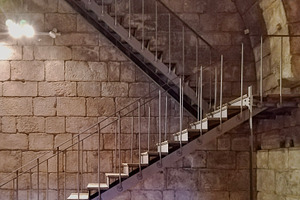 Modern stairs crossing medieval stone interior, an Architecture Photo by DanFLCreativo