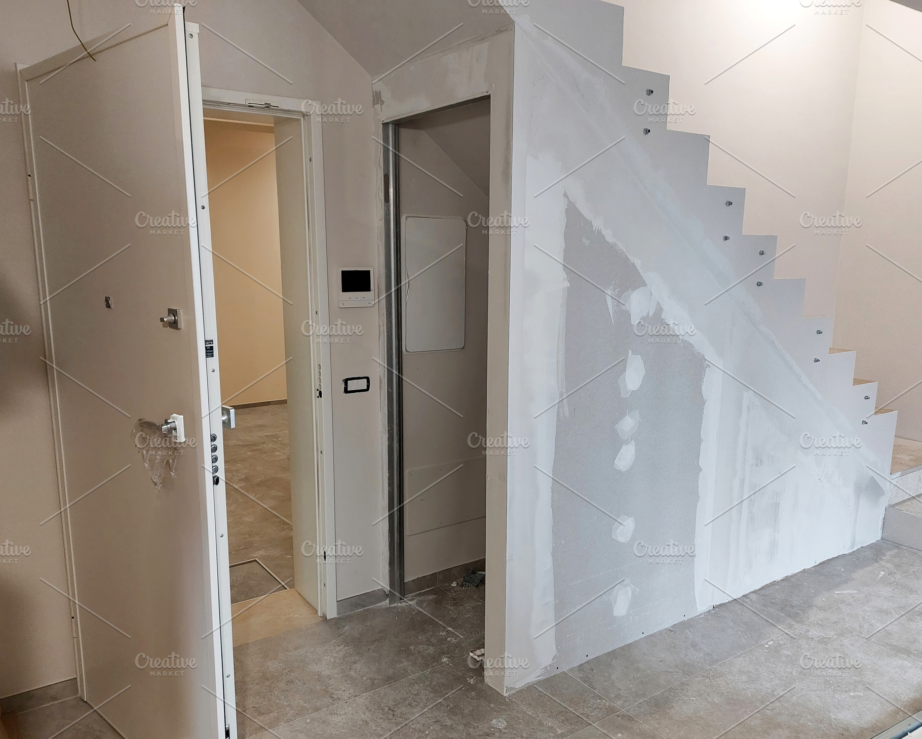 Workers renovating a house using plasterboard and stucco under the stairwell, an Architecture Photo by Antonio Gravante Market