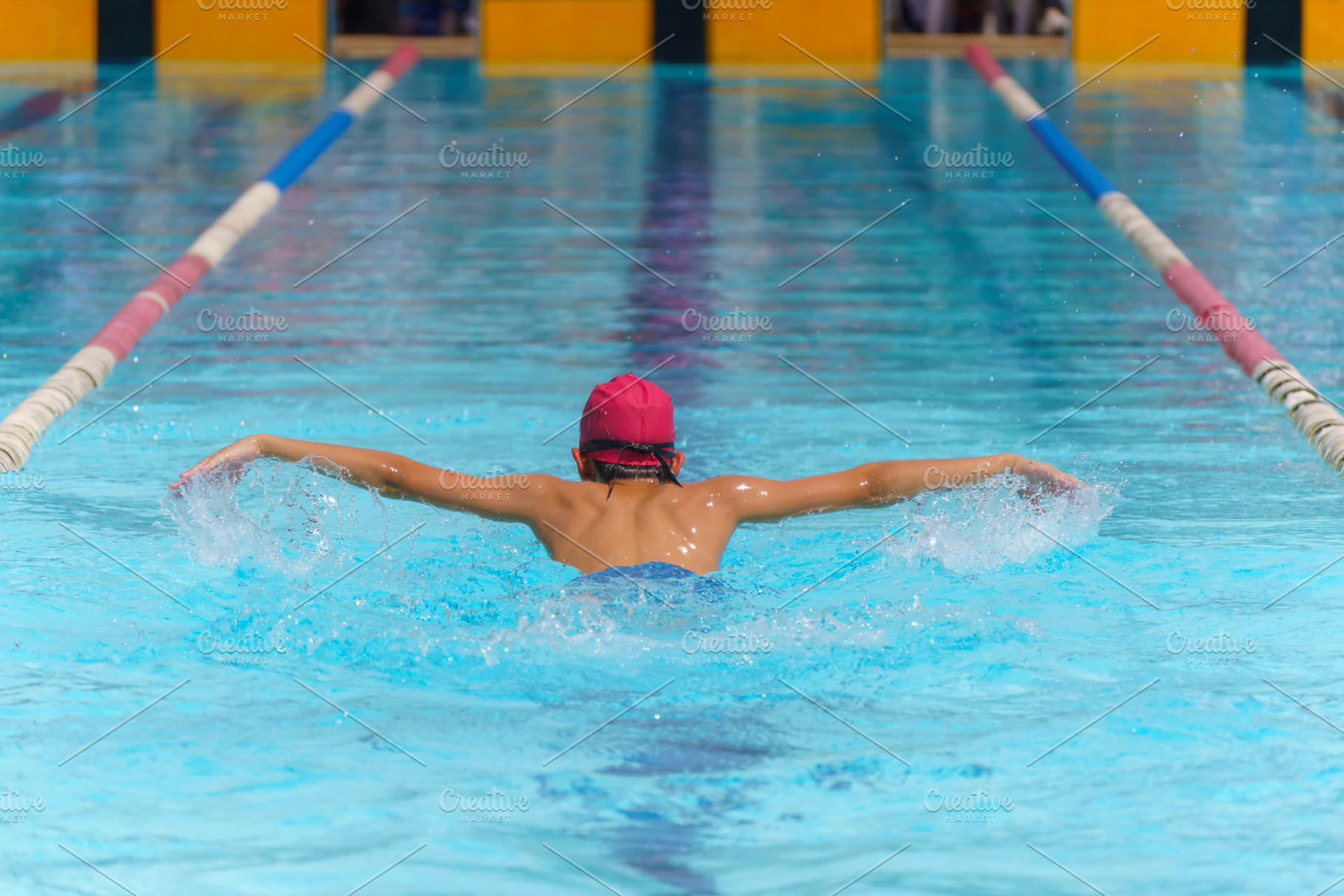 Swimmer child swims butterfly swimming style in a race swimming, a Photo by Casanowe-studio
