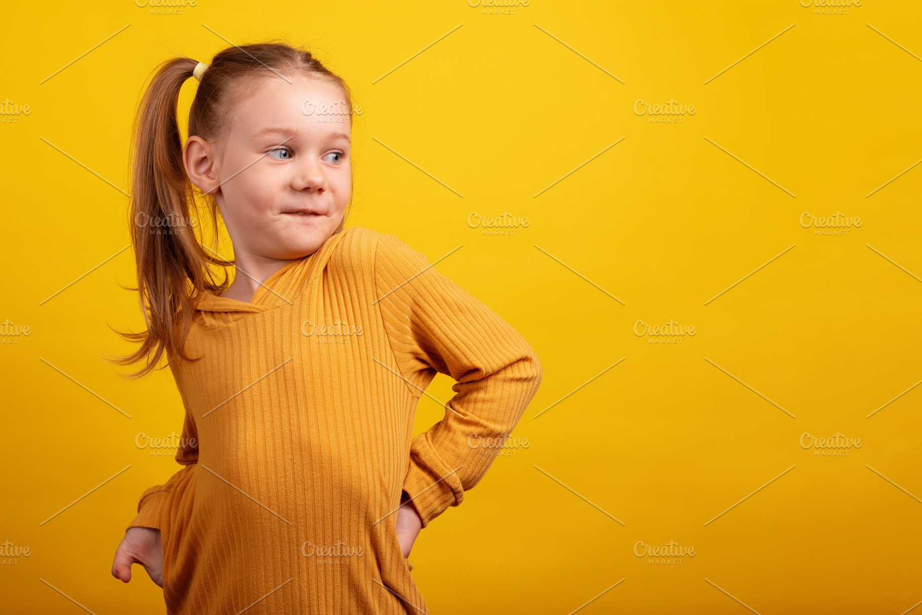 Young girl in a mustard sweater playfully looking over her shoul, a Person Photo by Ales Munt