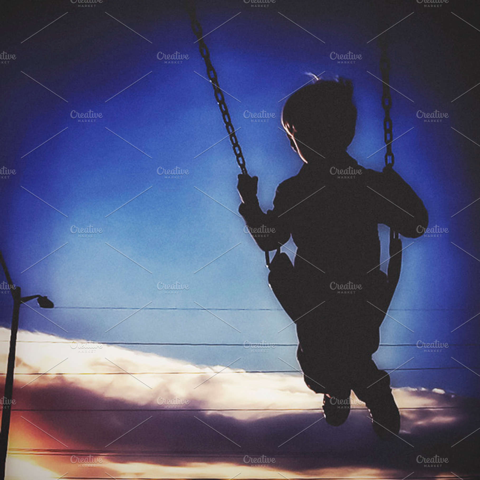 Silhouette of Boy Swinging at Sunset
