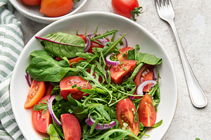 Fresh green salad with tomatoes and red onion, a Food & Drink Photo by Olena Rudo