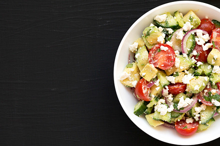 Delicious Avocado Tomato and Cucumber Salad in a white bowl on a, a Food & Drink Photo by LiudmylaChuhunova