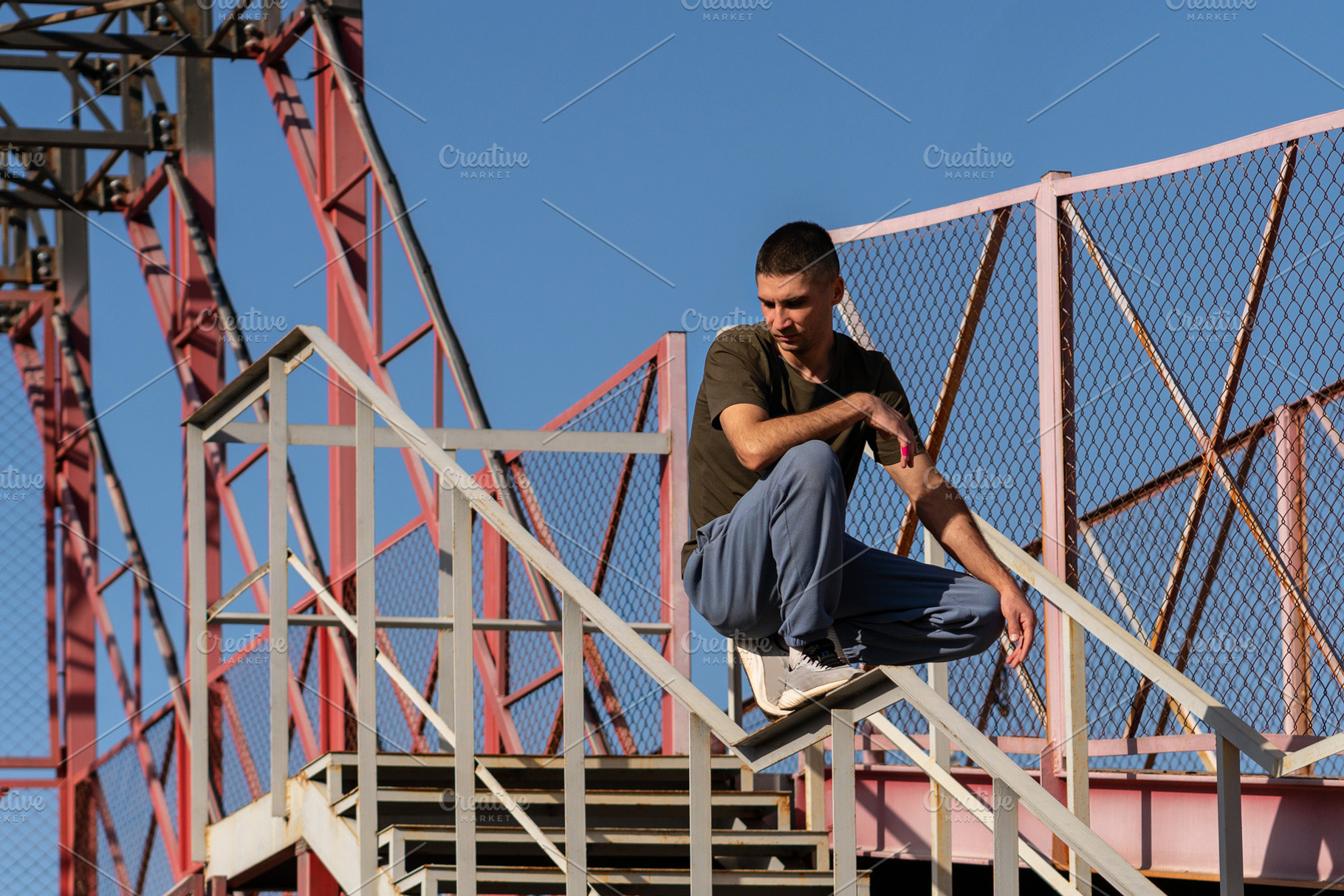 Man crouches on stair handrail, a Person Photo by Elena Vagengeim