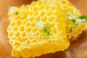 Fresh honeycomb with flower on wooden plate and honey in glass j, a Food & Drink Photo by Olena Rudo