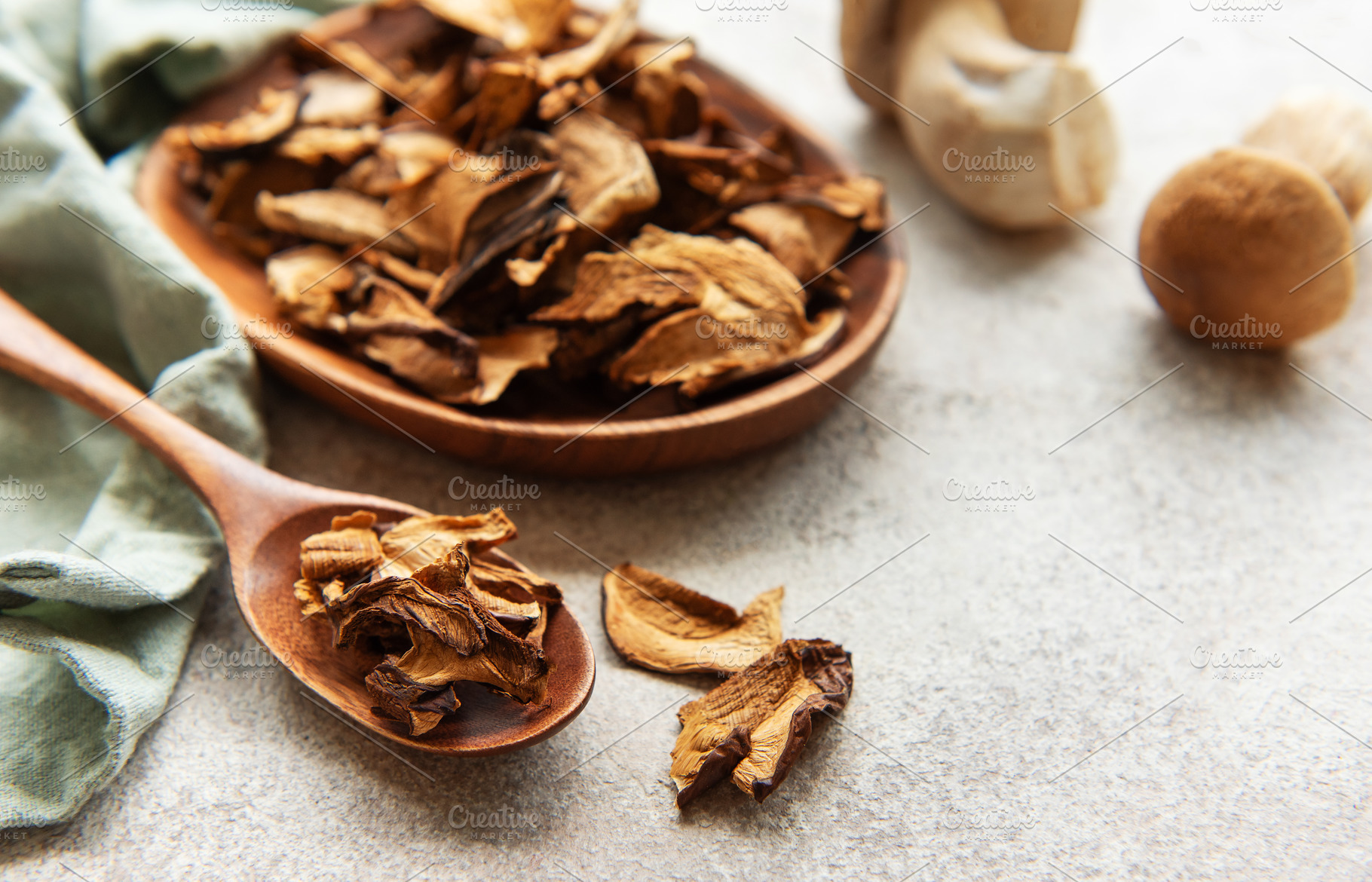 Dried mushrooms on wooden spoon and bowl, fresh mushrooms on gre, a Food & Drink Photo by Olena Rudo