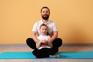 Smiling bearded man and young girl sitting on yoga mat in casual, a Person Photo by Ales Munt