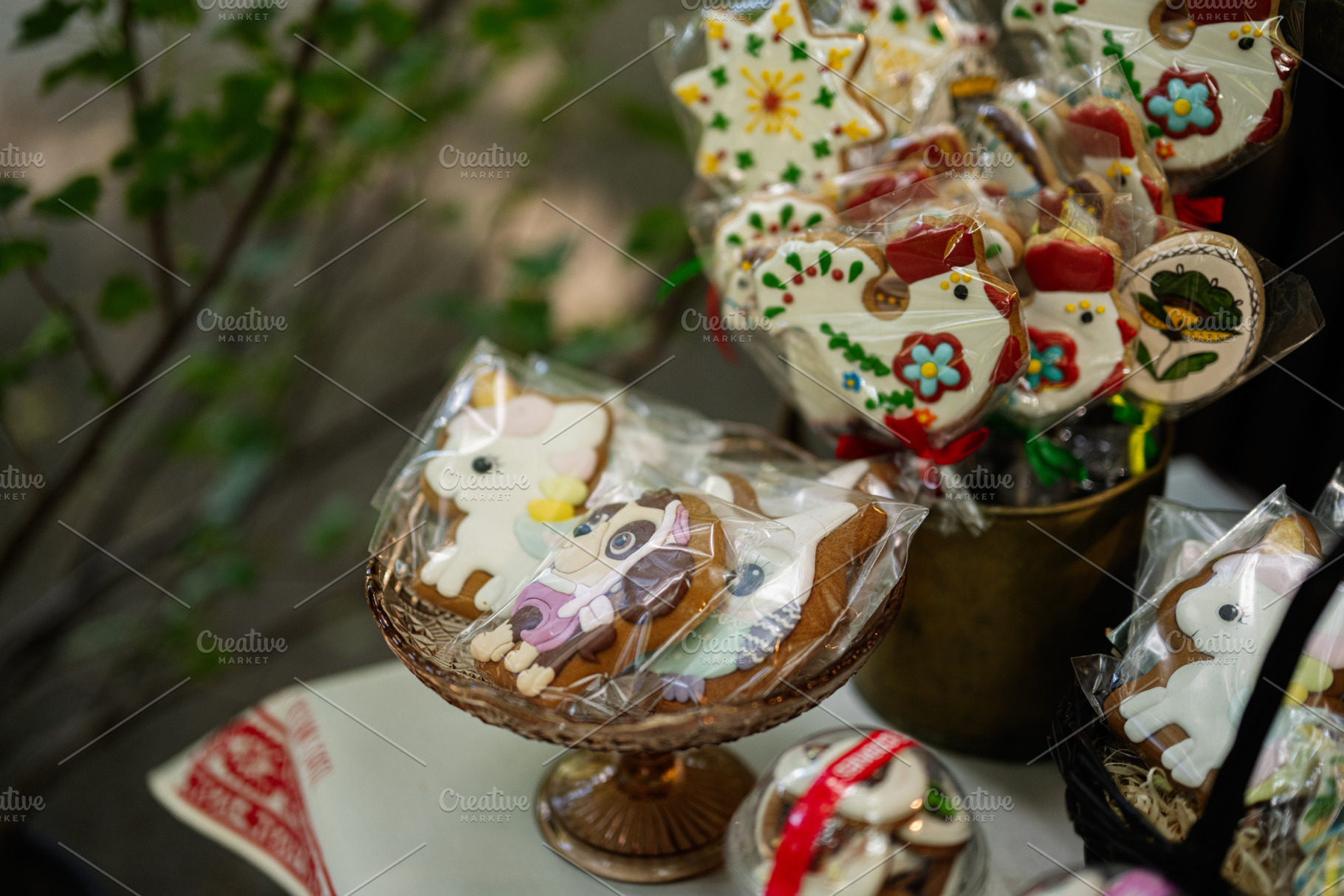Colorful decorated cookies displayed in a glass bowl on outdoor table, a Photo by AS photostudio