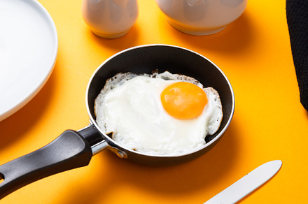 Scrambled, frying  eggs from one egg in a small pan on yellow ba, a Food & Drink Photo by MDBildes