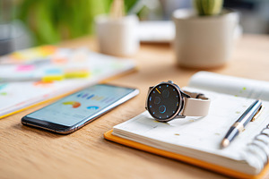 Smartphone and smartwatch on a wooden table with notes and stationery in a mode, a Business Photo by AlyaAnd