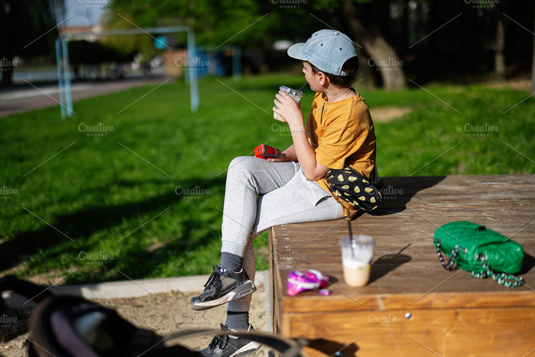 Young boy sitting outdoors enjoying a drink on a sunny day, a Person Photo by AS photostudio