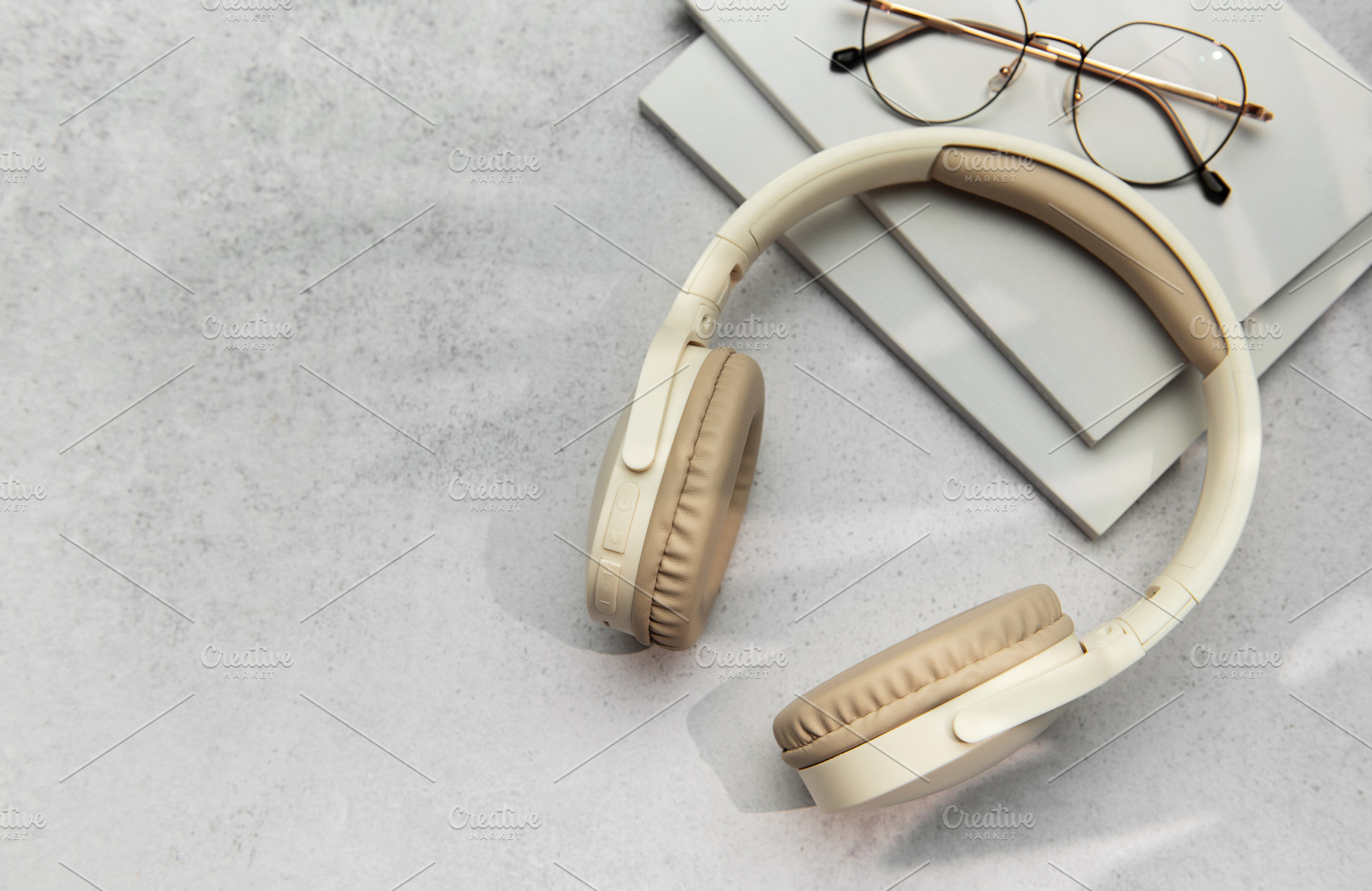 Modern wireless headphones lying on table next to books and eyeg, a Technology Photo by Olena Rudo