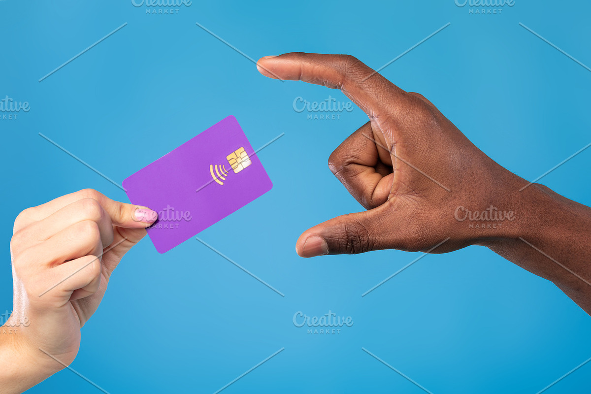 Closeup view of young woman giving credit card to African American man on blue, a Photo by Prostock-Studio (Photo 1 of 2)