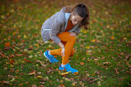 sad fit woman in fitness clothes in park having leg pain, a Sports & Recreation Photo by Alliance Images