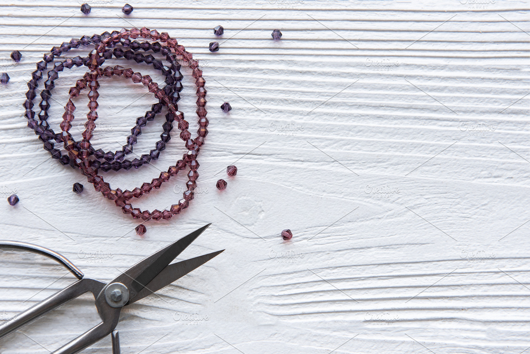Crafting with beads and scissors on a white wooden surface durin, a Beauty & Fashion Photo by Olena Rudo