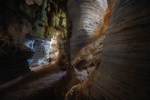 Man exploring the cave in Tam See Fah or Blue cave in Tak provin