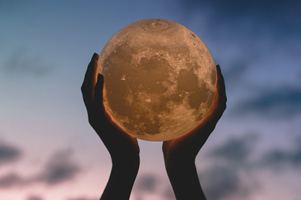 Hands holding up moon stock photo containing sky and clouds