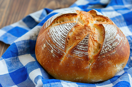 Freshly baked bread with blue napkin on wooden table, a Food & Drink Photo by AlyaAnd