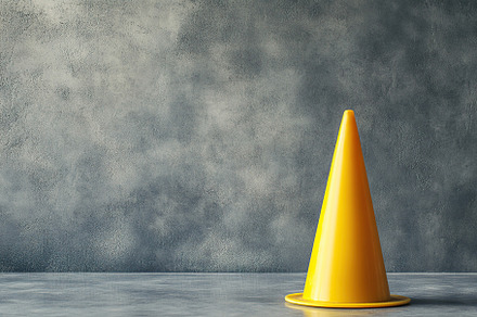 Yellow road cone placed against a textured grey wall in an indoo, an Industrial Photo by AlyaAnd