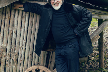 elderly man with a beard stands in the village near a wooden shed in a sheepski, a Person Photo by SaulichPhoto