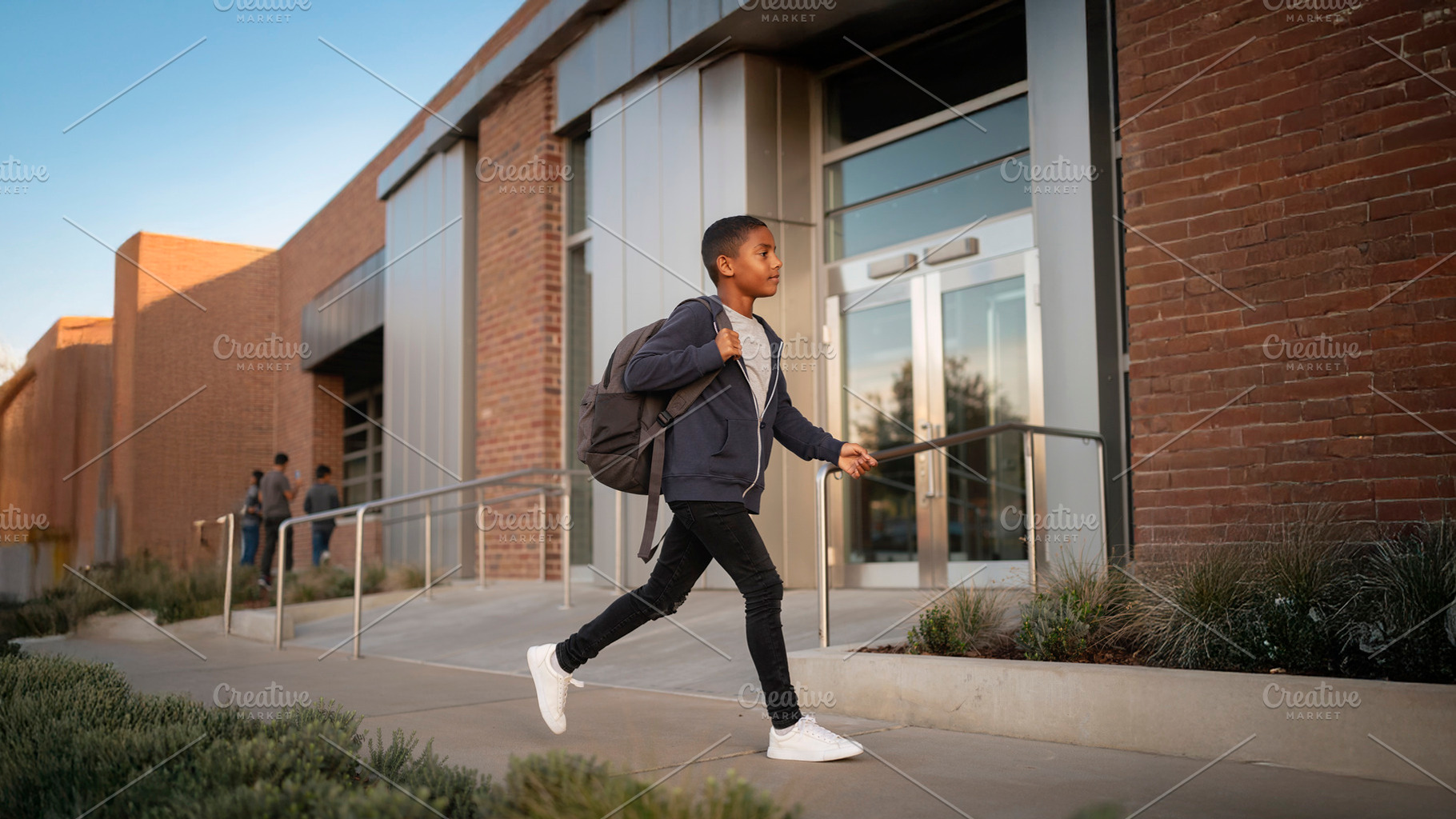 Black middle school student walking toward a school entrance wit, a School & Education Photo by DanFLCreativo