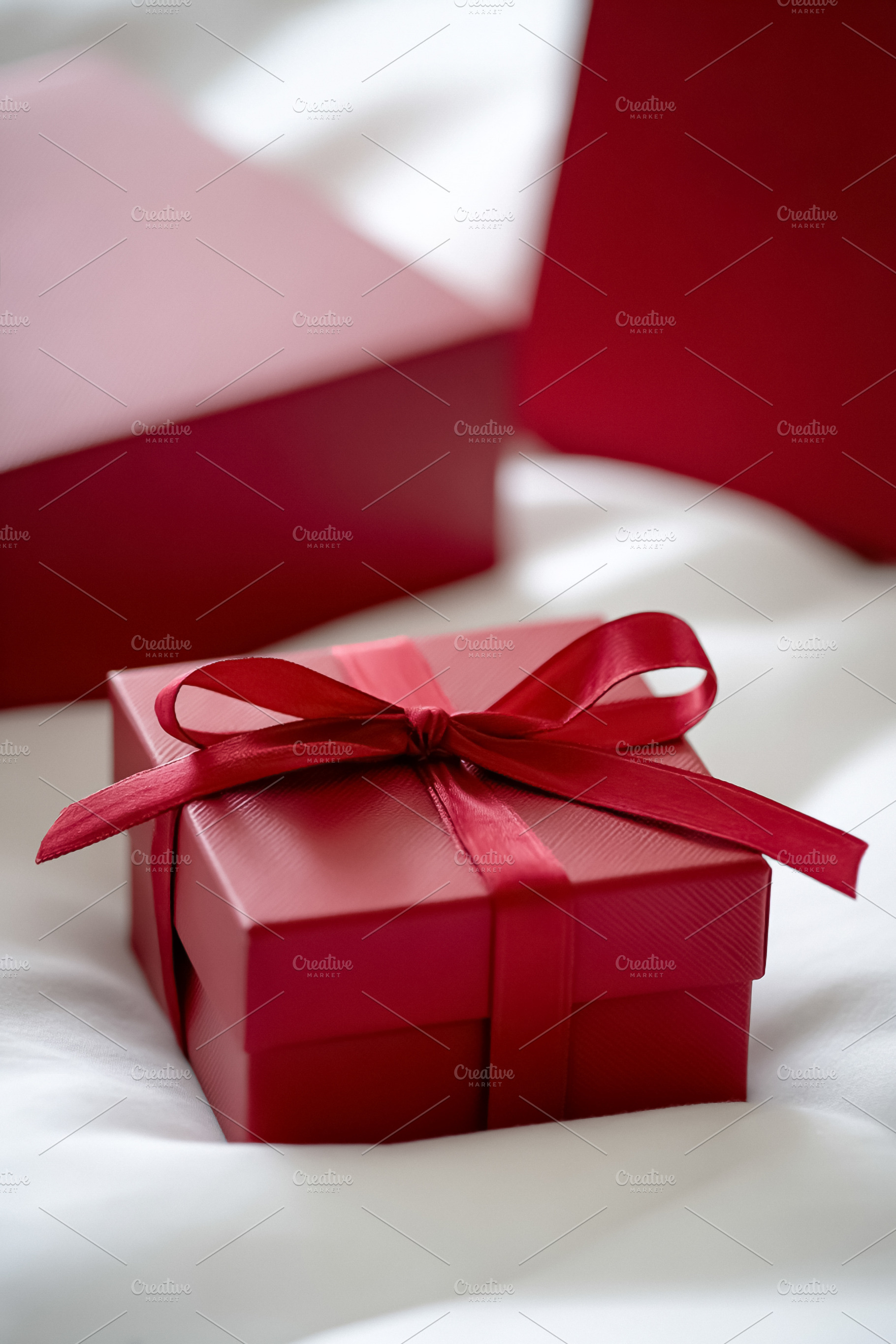 Red gift box with ribbon and bow representing a surprise present, a Photo by Studio ANNA